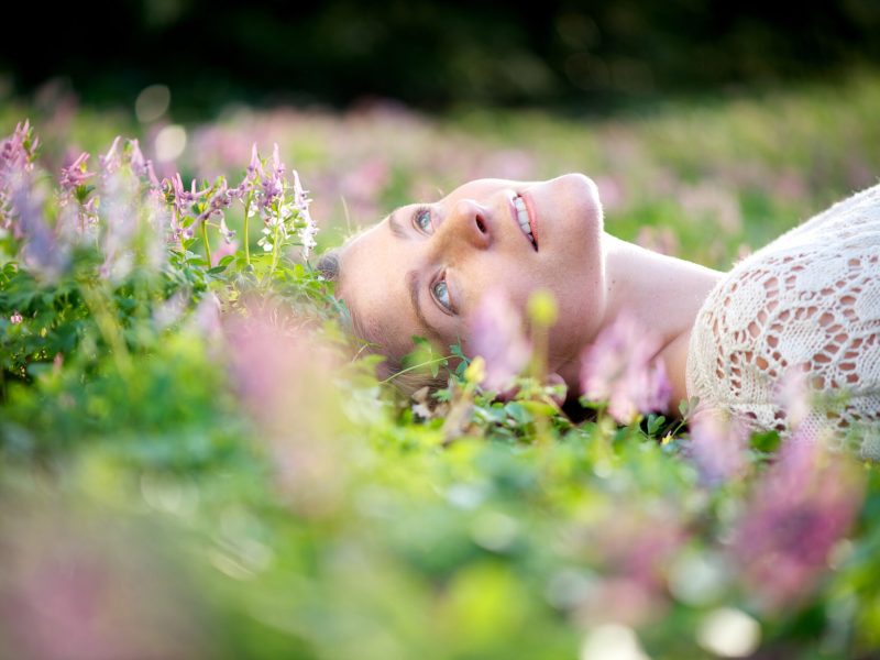 Portrait of a beautiful young woman lying in meadow of flowers